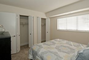 Silver Spring apartment for rent - A bedroom with a bed, dresser, and three open closet doors.