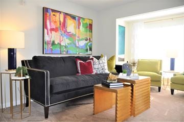 High Point apartment for rent - A living room with a black couch, a green chair, and a painting on the wall.