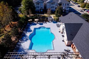 Hattiesburg apartment for rent - A large swimming pool surrounded by a metal fence and a few trees.