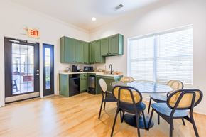 Hattiesburg apartment for rent - A kitchen with green cabinets and a dining table with chairs.
