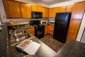 Charlotte apartment for rent - A kitchen with wooden cabinets and a black refrigerator.