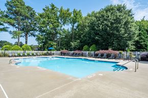 Goldsboro apartment for rent - A large outdoor swimming pool surrounded by trees and a fence.