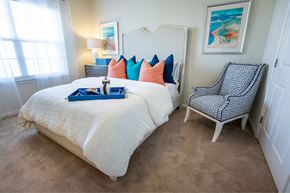 New Bern apartment for rent - A bedroom with a white bed and a chair with a black and white pattern.