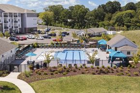 Fort Mill apartment for rent - A large swimming pool surrounded by a grassy area and trees.