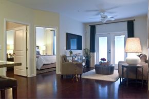 Wilmington apartment for rent - A well-lit bedroom with a bed, a couch, a chair, and a table with a lamp on it.