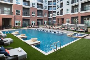 Frisco apartment for rent - A large outdoor swimming pool surrounded by lounge chairs and umbrellas.