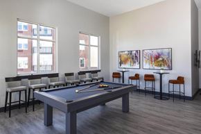 Belleville apartment for rent - A pool table is in the middle of a room with bar stools and paintings on the wall.