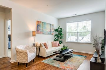 Mount Laurel apartment for rent - A living room with a white couch, a chair, a coffee table, and a painting on the wall.