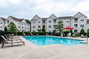 Mount Laurel apartment for rent - Mt. Laurel Township, NJ, Garden-Style Apartments Near Joint Air Force Base - Laurel Green - Saltwater Swimming Pool with Lounge Chairs, Umbrella, and View of Apartment Buildings.