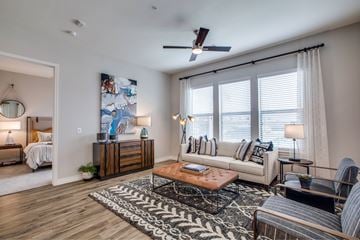 Spring apartment for rent - A living room with a large painting on the wall and a wooden floor.