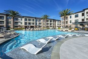 Spring apartment for rent - A large swimming pool with sun loungers in front of apartment buildings.