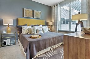 Houston apartment for rent - A bedroom with a large bed and a nightstand with a lamp.
