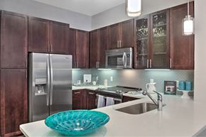 Houston apartment for rent - A kitchen with brown cabinets and a stainless steel refrigerator.