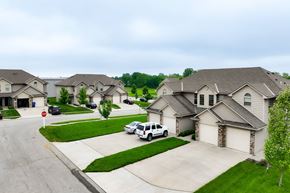 Peculiar apartment for rent - A white car is parked in front of a house in a residential neighborhood.