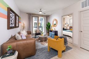 Austin apartment for rent - A living room with a brown couch, a yellow chair, and a ceiling fan.