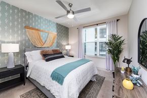 Austin apartment for rent - A bedroom with a bed, a ceiling fan, and large window
