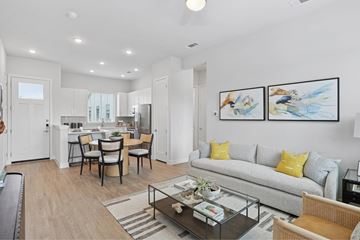 Fort Worth apartment for rent - A modern living room with a grey sofa, a glass coffee table, and a dining table with chairs.