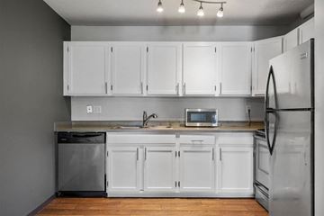 Little Canada apartment for rent - A kitchen with white cabinets and a stainless steel refrigerator.