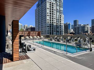 Chicago apartment for rent - A rooftop pool area with lounge chairs and a view of the city skyline.