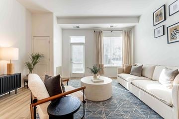 Eden Prairie apartment for rent - A living room with a white couch, a wooden chair, and a small table with a vase on it.