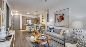 Allen apartment for rent - A modern living room with a grey sofa, a wooden coffee table, and a large abstract painting on the wall.