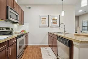 Mckinney apartment for rent - A kitchen with brown cabinets and a white dishwasher.