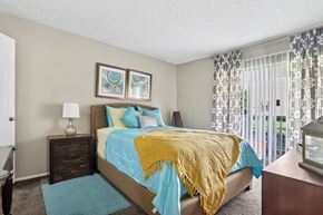 Dallas apartment for rent - A bedroom with a bed covered in a blue and yellow comforter.