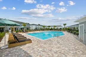 Jacksonville apartment for rent - A pool surrounded by lounge chairs and umbrellas.