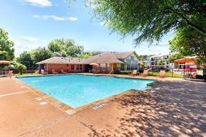 Dallas apartment for rent - A large outdoor swimming pool with a building in the background.