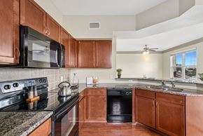 San Antonio apartment for rent - A kitchen with brown cabinets and black appliances.