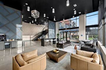 Huntsville apartment for rent - A modern living room with tan couches and a staircase in the background.