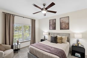 Conroe apartment for rent - A bedroom with a bed, chair, and window.