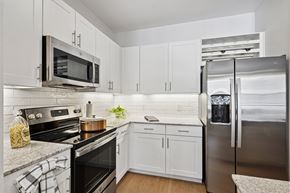 Carrollton apartment for rent - A kitchen with white cabinets and a black stove top.