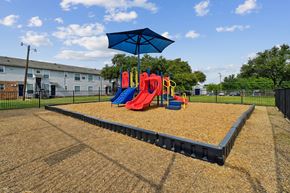 Dallas apartment for rent - A playground with a slide, swings, and a blue umbrella.