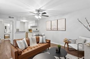 Houston apartment for rent - A living room with a brown couch and a ceiling fan.