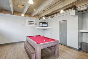 Nashville apartment for rent - A pool table in a room with a concrete ceiling and wooden flooring.