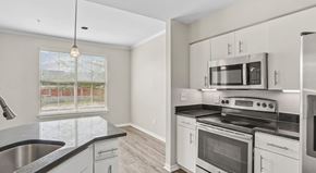 Dallas apartment for rent - A kitchen with white cabinets and black countertops.