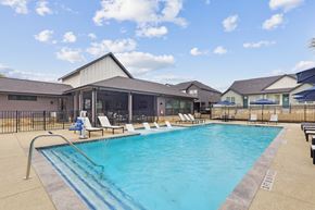 Fulshear apartment for rent - A large swimming pool with lounge chairs and a building in the background.