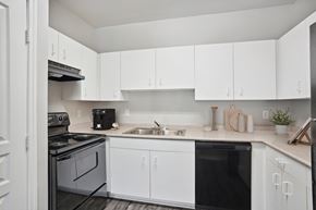 Arlington apartment for rent - an empty kitchen with white cabinets and black appliances