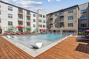 Fort Worth apartment for rent - A large outdoor pool surrounded by wooden decking and lounge chairs.