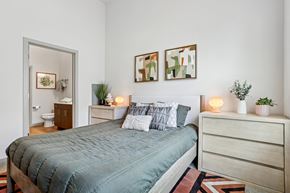 Carrollton apartment for rent - A bedroom with a bed, nightstand, and two framed pictures on the wall.