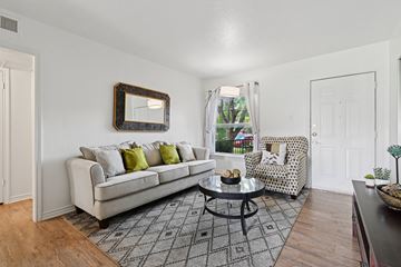 Dallas apartment for rent - A living room with a white couch, a coffee table, and a chair with a patterned cushion.