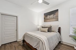 Charlotte apartment for rent - A bedroom with a bed, pillows, a ceiling fan, and a picture on the wall.