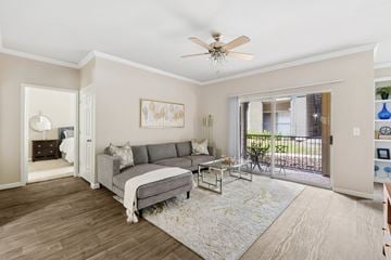 San Antonio apartment for rent - A living room with a grey couch and a ceiling fan.