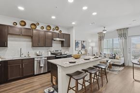 Forney apartment for rent - A modern kitchen with brown cabinets and a white island.