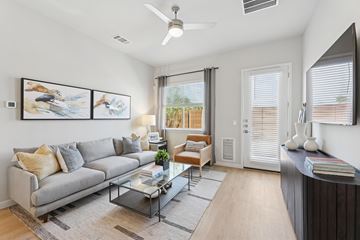 Hutto apartment for rent - A living room with a grey sofa, a glass coffee table, and a painting on the wall.