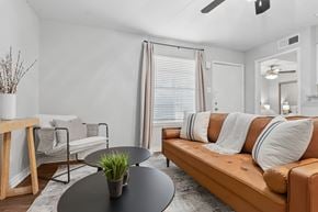 Houston apartment for rent - A living room with a brown couch, a black table, and a plant on it.
