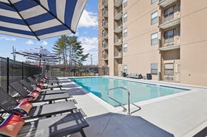 Madison apartment for rent - A pool area with sun loungers and a tall building in the background.