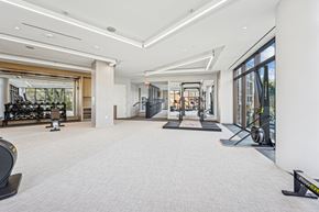 Bethesda apartment for rent - A spacious gym with a variety of equipment and a large mirror on the wall.