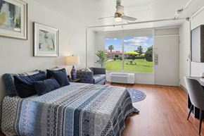 San Marcos apartment for rent - A bedroom with a bed, a chair, and a window overlooking a green lawn.